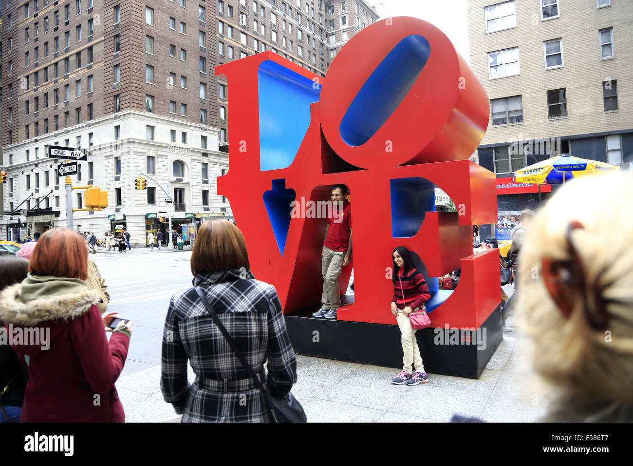 Besucher, die ihre Fotos vor der Love-Skulptur an der 6th Avenue. Midtown Manhattan, New York City, USA Stockfoto