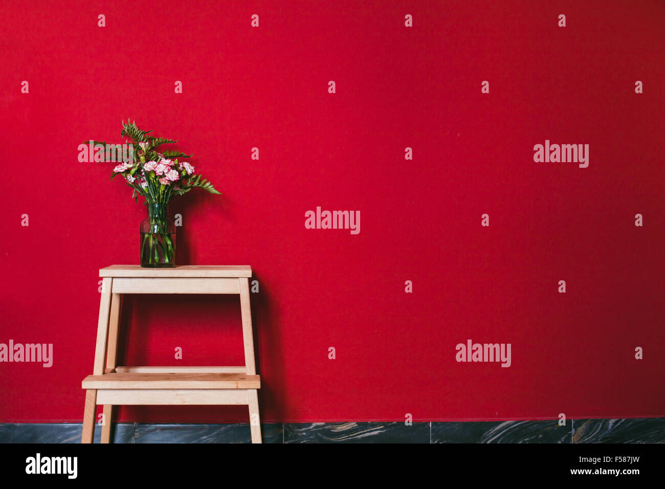 schlichtes Design, Interieur, Blumen in Vase auf der roten Wand Hintergrund Stockfoto