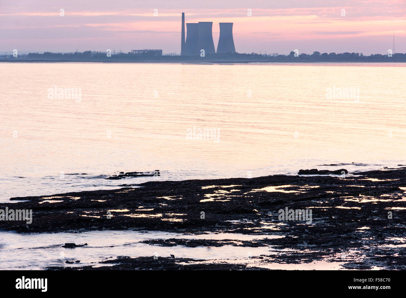 England, Ramsgate, Pegwell Bay. Abendhimmel über Küste an der Oberseite des Rahmens mit Silhouettiert power station am Horizont. Felsen und Meer im Vordergrund. Stockfoto