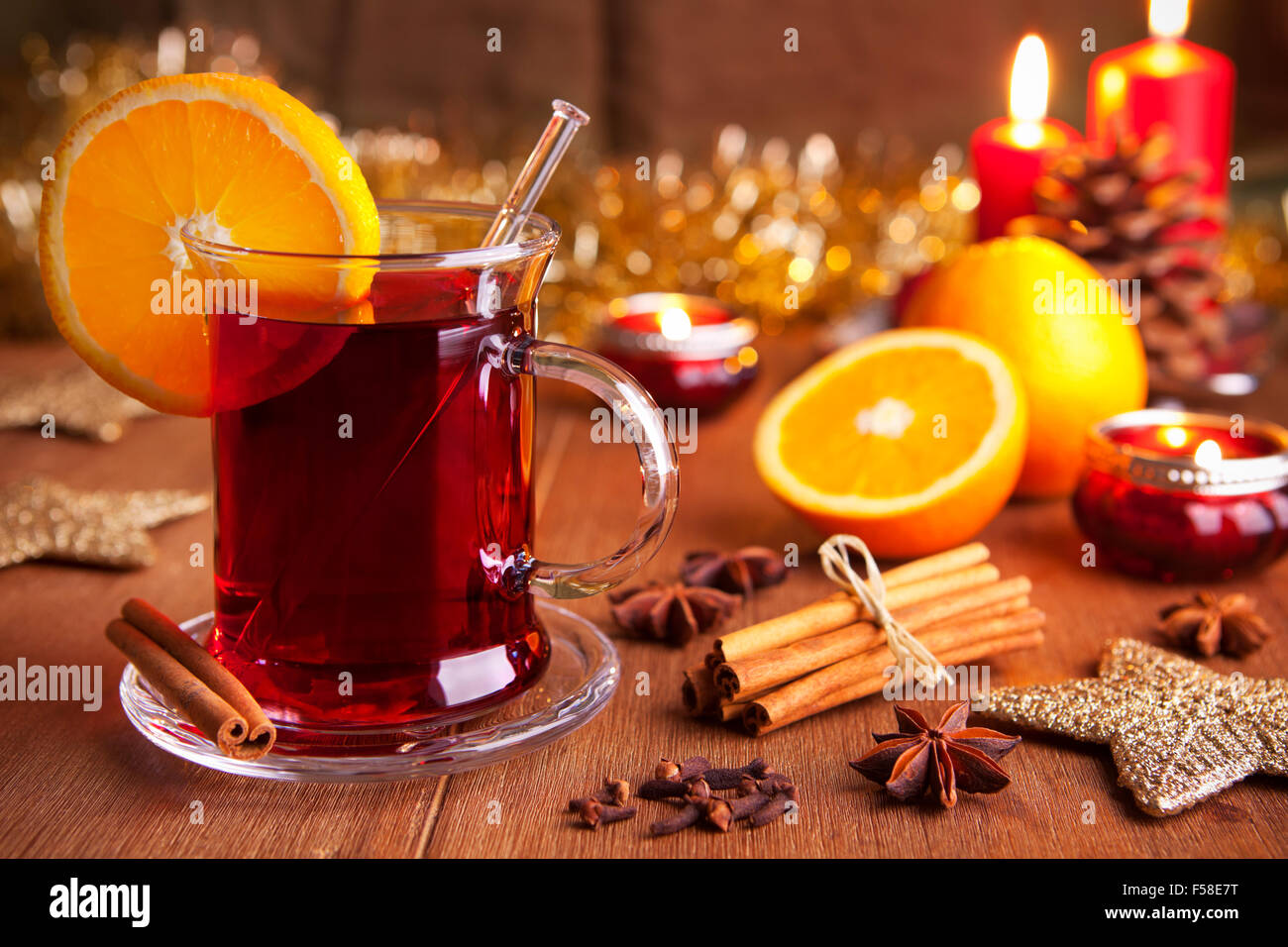 Ein Glas Glühwein oder Glühwein auf einem rustikalen Tisch mit Zutaten und Weihnachtsschmuck. Stockfoto