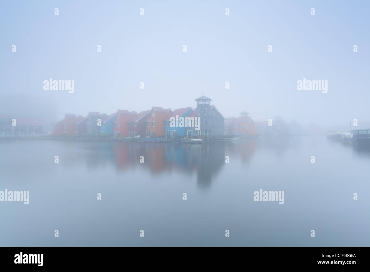 bunte Gebäude auf dem Wasser in nebligen Morgen, Groningen, Niederlande Stockfoto