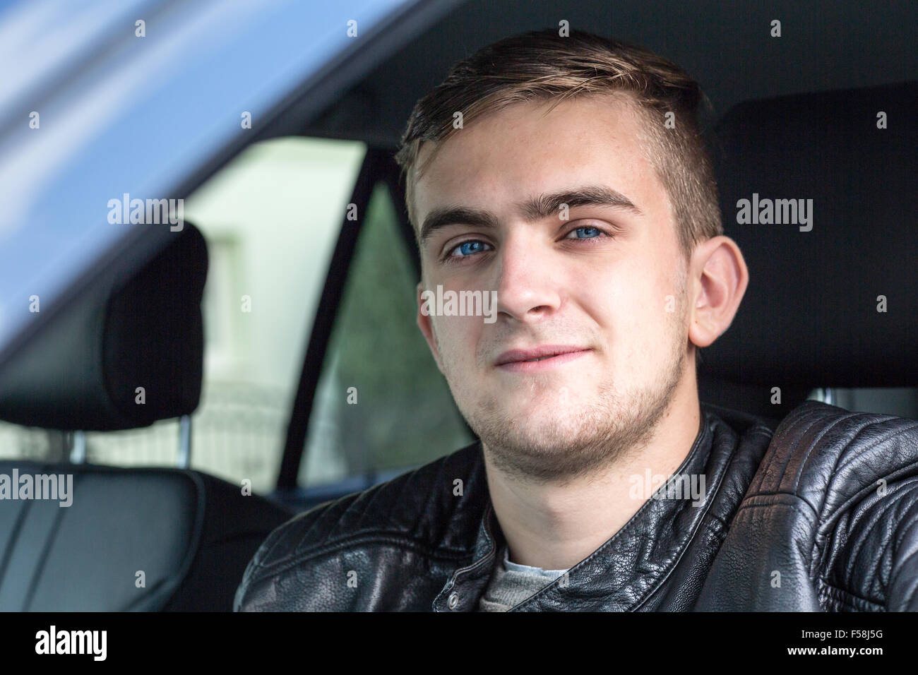 glückliche junge blonde Erwachsene im Inneren eines Autos. glücklich, seinen neuen Führerschein zu haben. Stockfoto