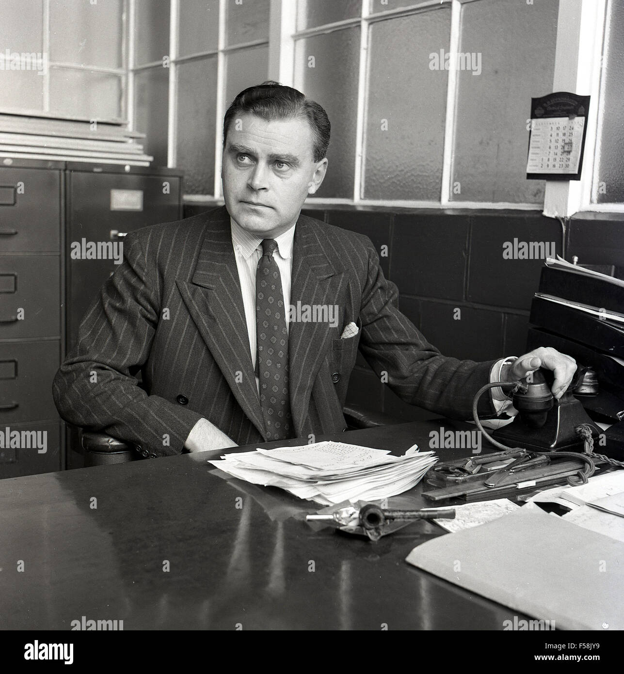 1950er Jahre historische, Geschäftsführer im Amt mit Papierkram und Pfeife  auf Schreibtisch und Telefon Stockfotografie - Alamy
