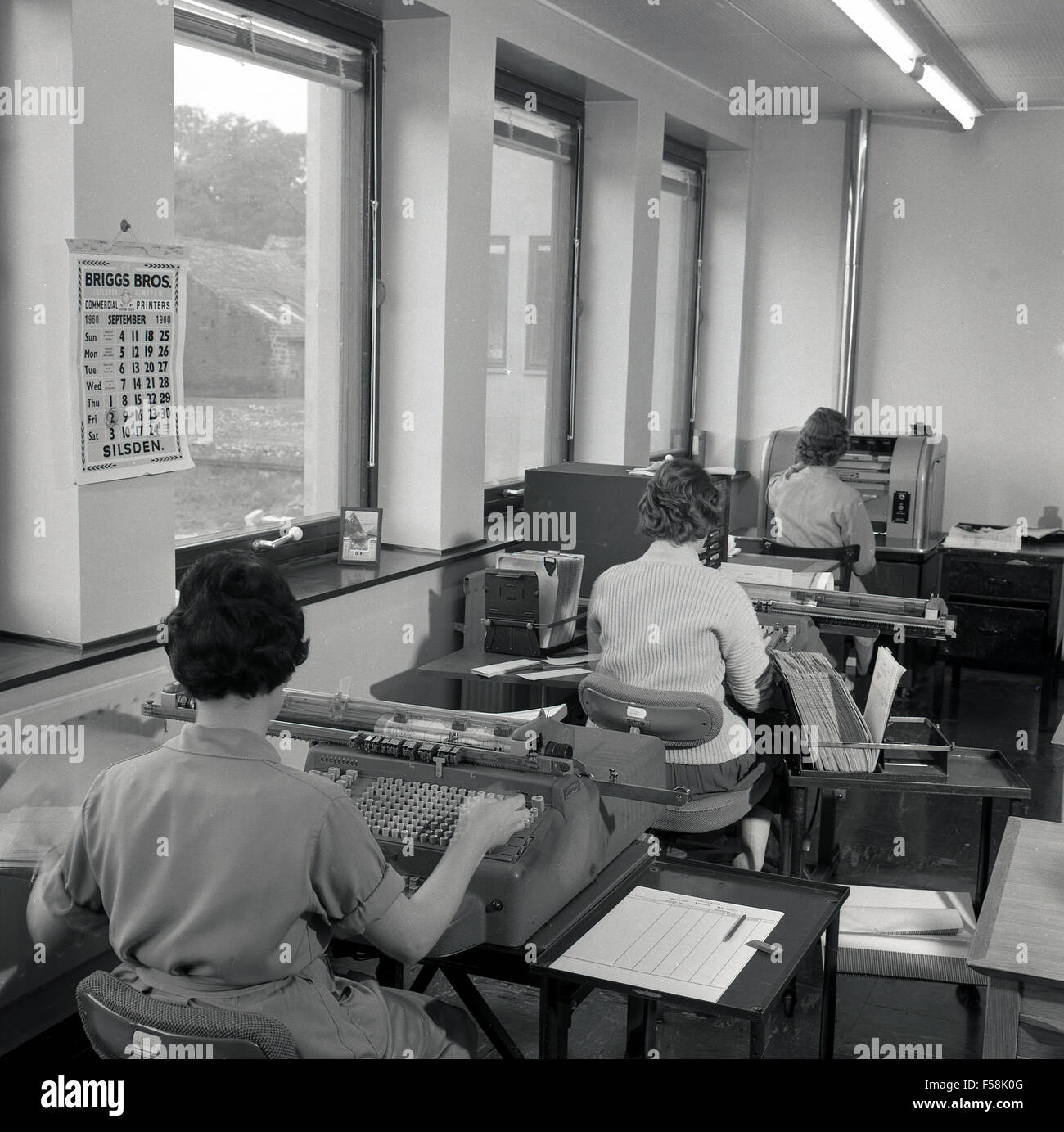 1950er Jahre, historische Büroangestellte an Schreibtischen, die in einem Büro mit großen Buchhaltungs- oder Datenverarbeitungsmaschinen im IBM-Stil arbeiten, England, Großbritannien. Stockfoto
