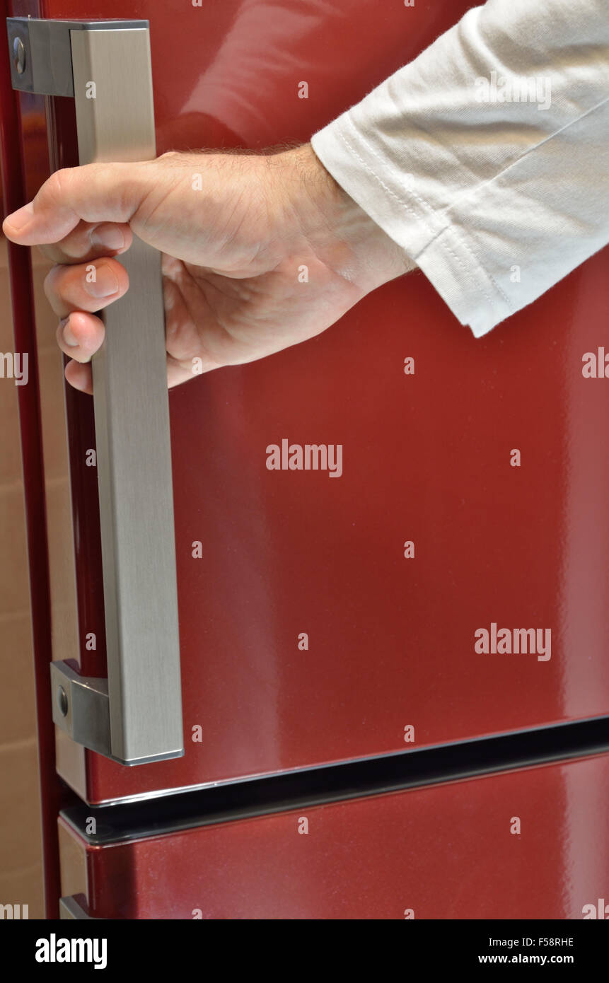 Hand auf den Türgriff des roten Kühlschrank Stockfoto