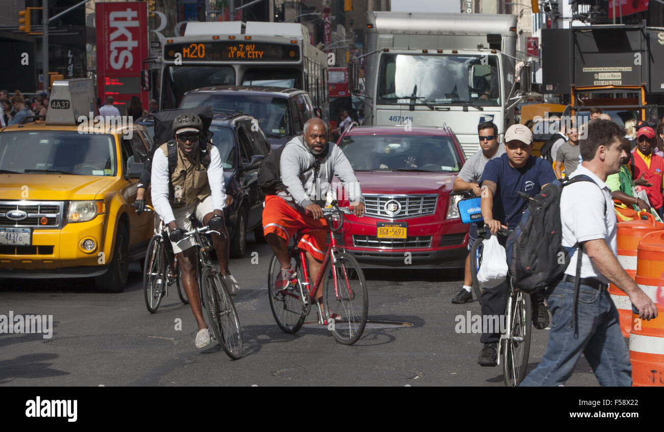 Mutige Fahrradkuriere fahren Fahrräder inmitten der ständigen Din Verkehr an der 7th Avenue in Times Square, New York. Stockfoto