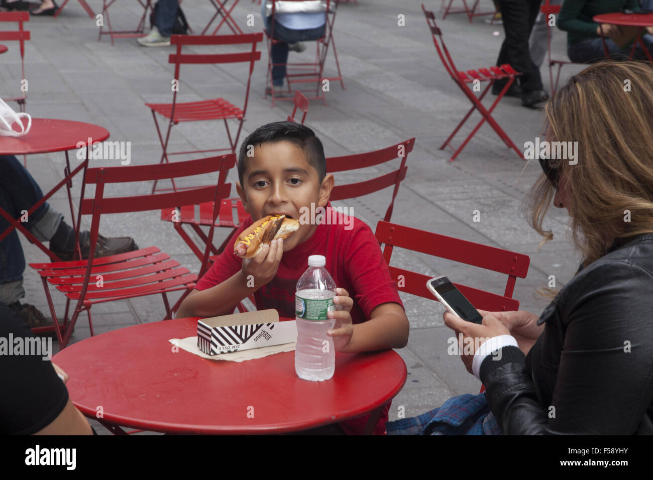 Junge frisst nach unten auf einen Hot Dog in Times Square in New York City. Stockfoto