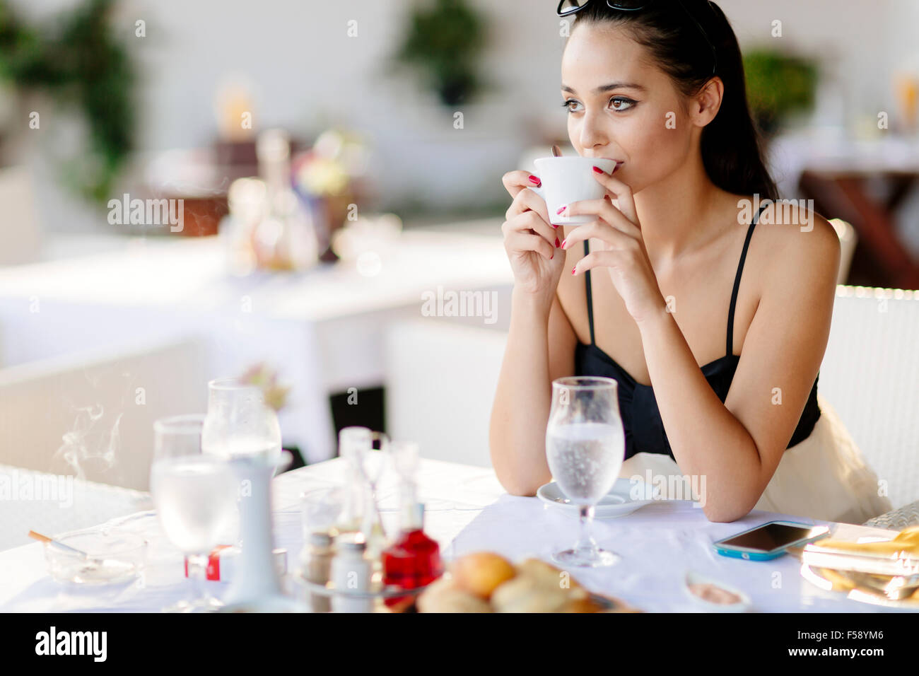 Schöne Frau trinkt Tee im Restaurant während des Wartens auf ihre Mahlzeit Stockfoto