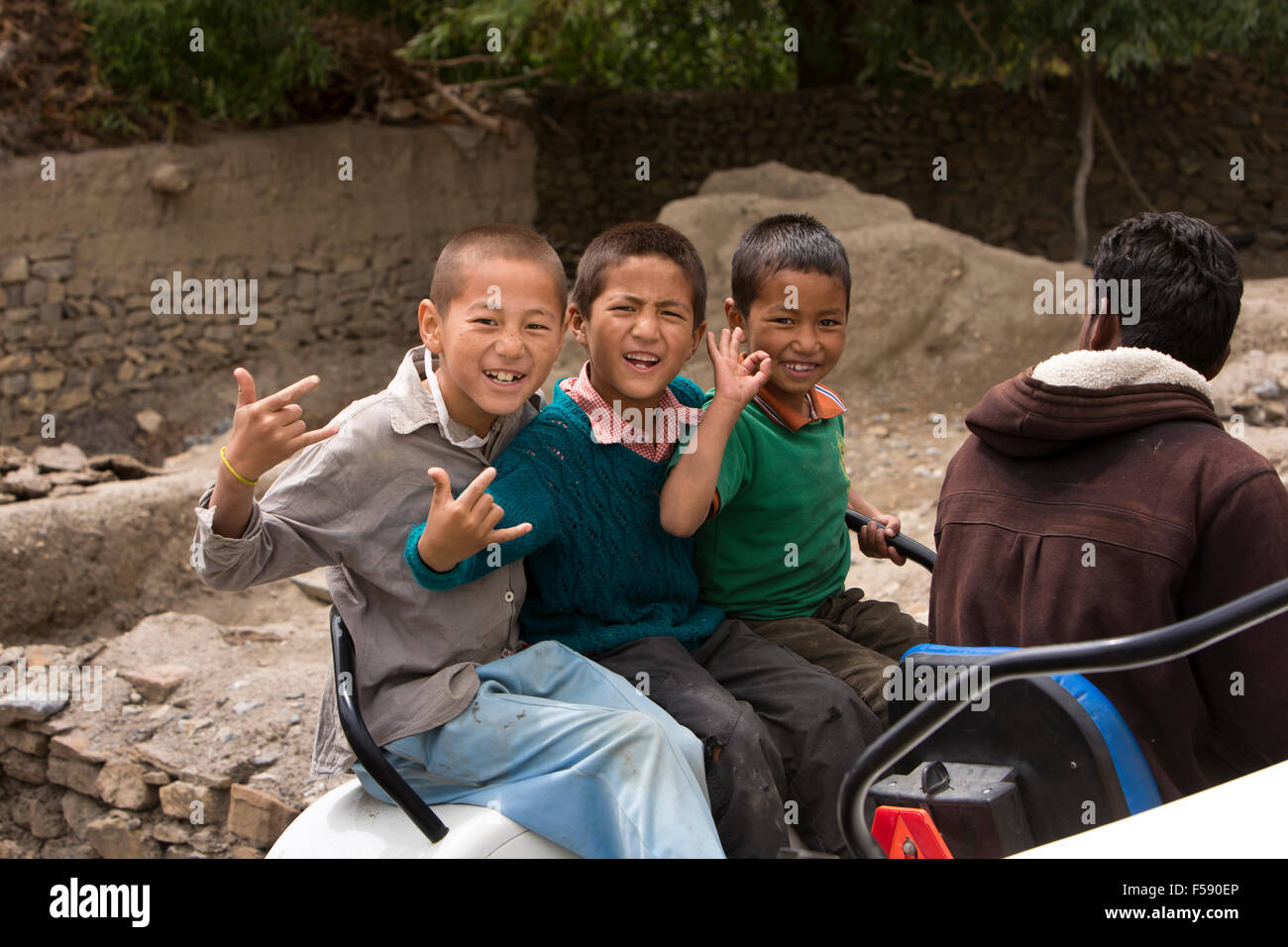 Indien, Himachal Pradesh, Spiti Valley, Khurik Dorf, drei junge Burschen Reiten auf Traktor machen Handgesten Stockfoto