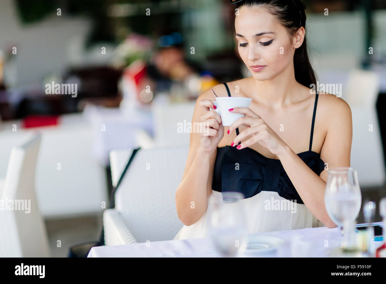 Schöne Frau trinkt Tee im Restaurant während des Wartens auf ihre Mahlzeit Stockfoto