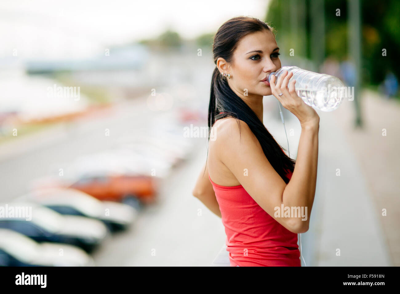 Durstige Frau Trinkwasser zu erholen nach dem Joggen Stockfoto