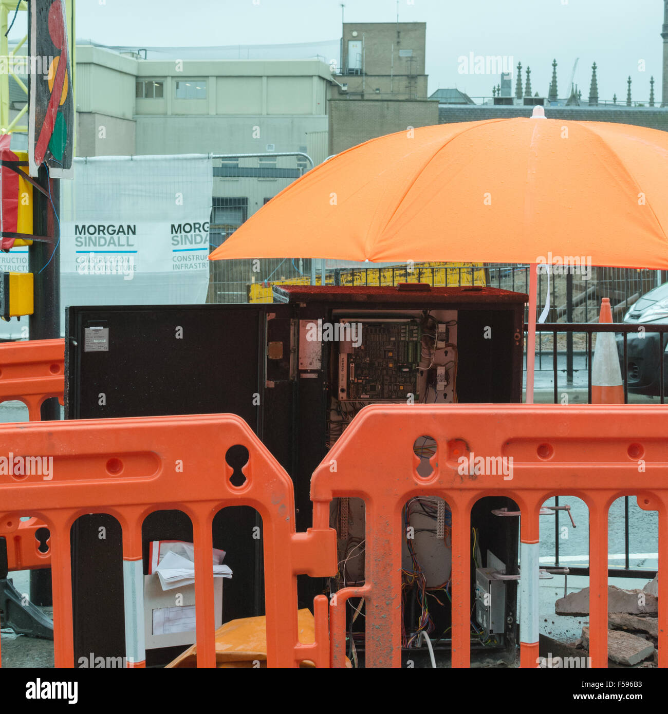 leuchtend orange Regenschirm Stromkreise vor dem Regen zu schützen, während der Straßenarbeiten Bauarbeiten im Zentrum von Aberdeen Stockfoto