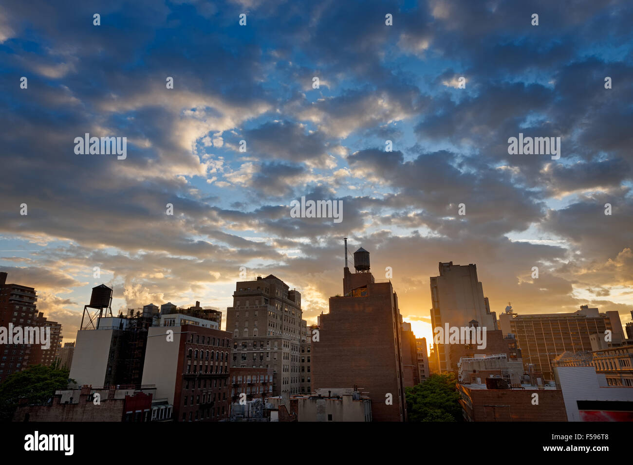 New York City, Chelsea-Viertel und die Skyline bei Sonnenuntergang mit Wassertanks punktiert. Entlang der 8th Avenue, Manhattan, NYC Stockfoto