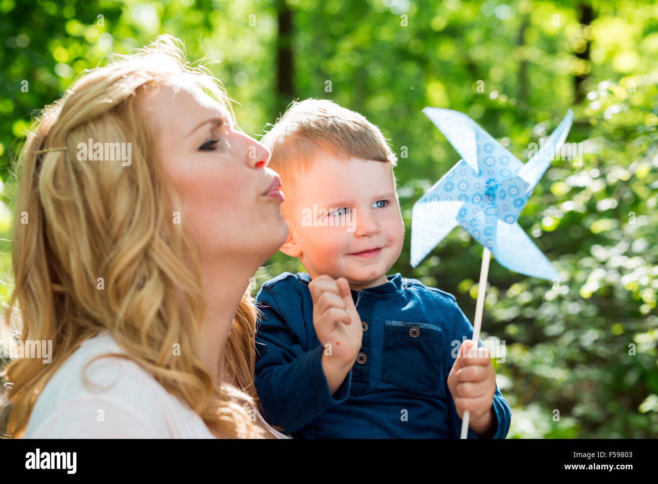 Schöne Frauen weht eine Papier-Windmühle mit ihrem kleinen Sohn Stockfoto