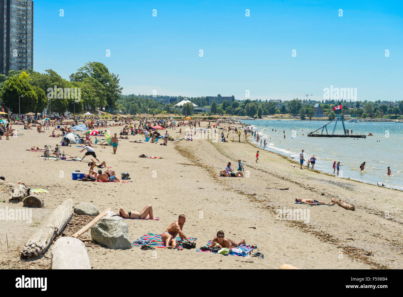 Sonnenanbeter und Badegäste am Strand von English Bay in Vancouver, BC, Kanada Stockfoto