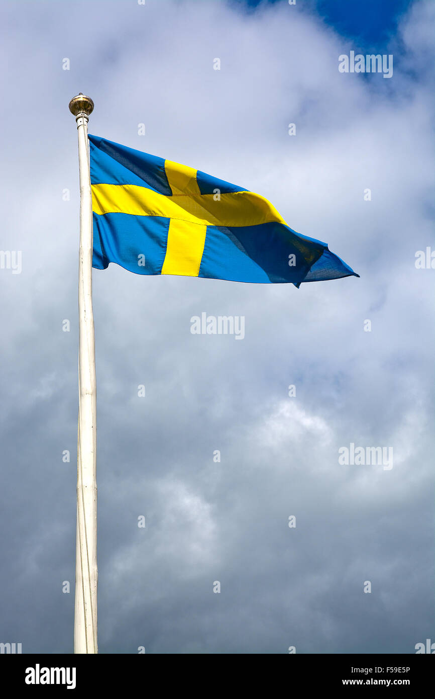 Schwedische Flagge gegen Sturm grauen Himmel bei Sonnenschein, Schweden. Stockfoto