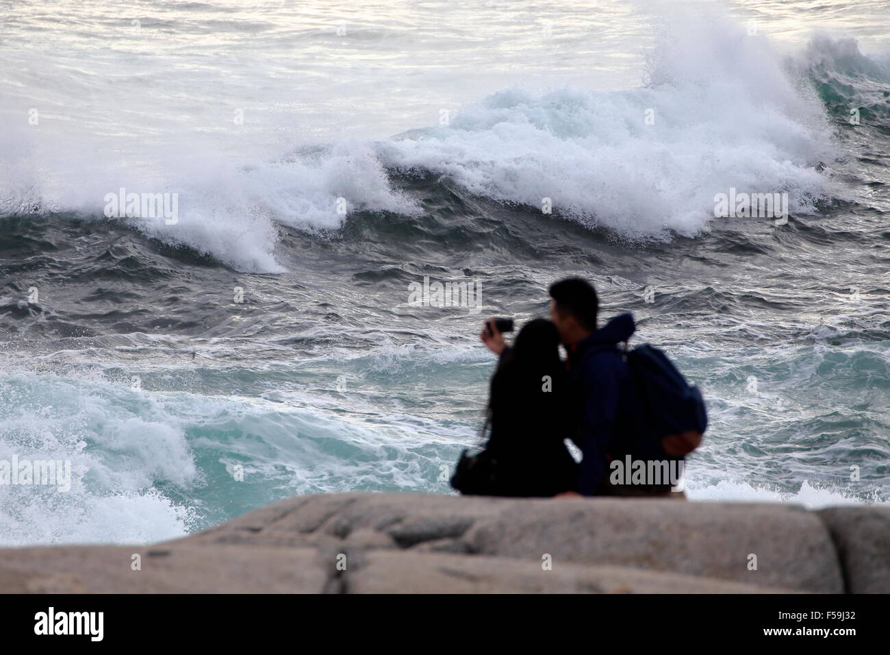 Ein paar oder zwei Menschen auf den Felsen bei Peggys Cove, Nova Scotia, die Nähe zu den Wellen und in der Gefahr des Ertrinkens. Stockfoto