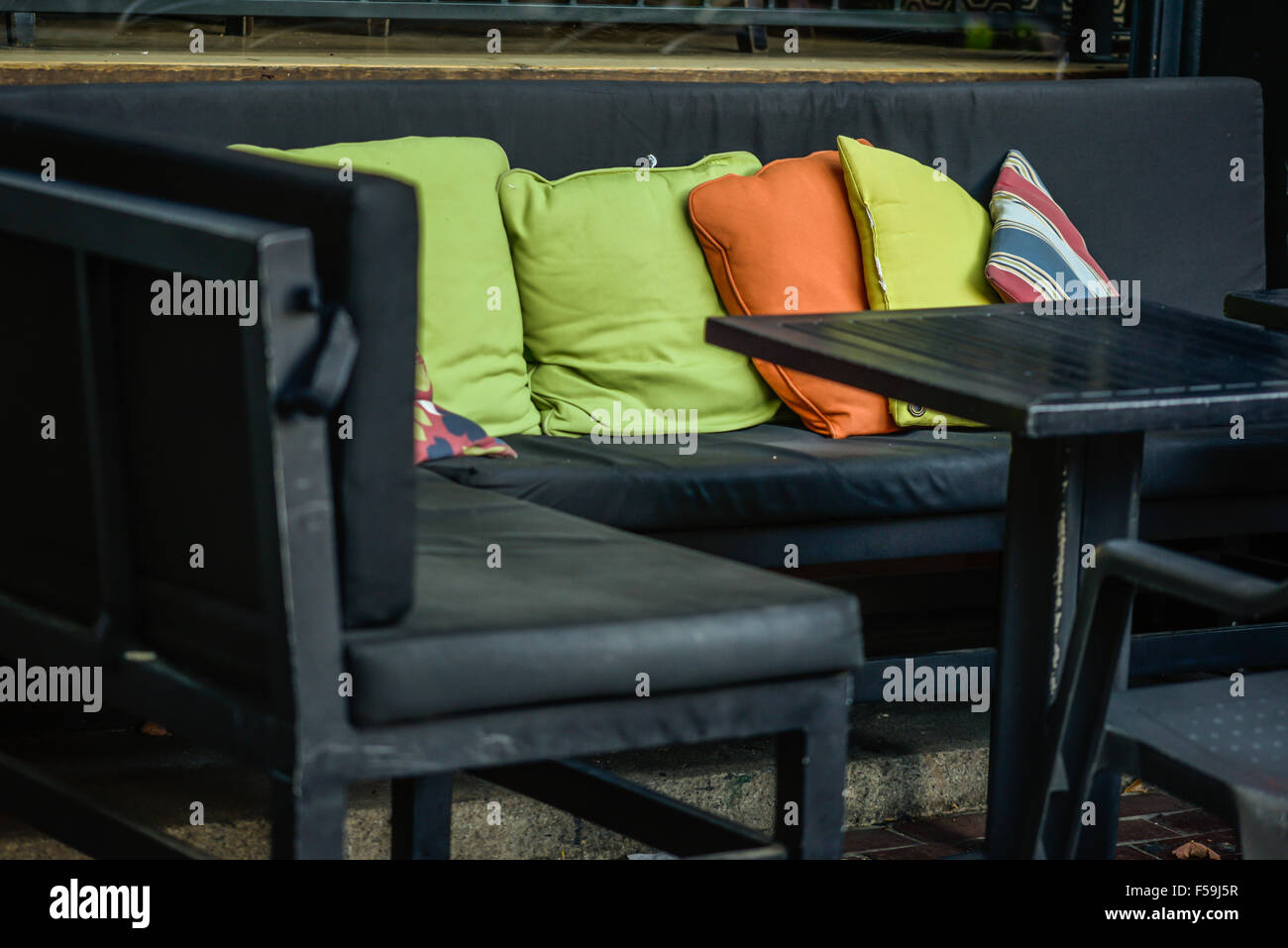 Bunte Kissen auf einer Terrasse Couch Tisch auf der Terrasse an einem bewölkten Tag Stockfoto
