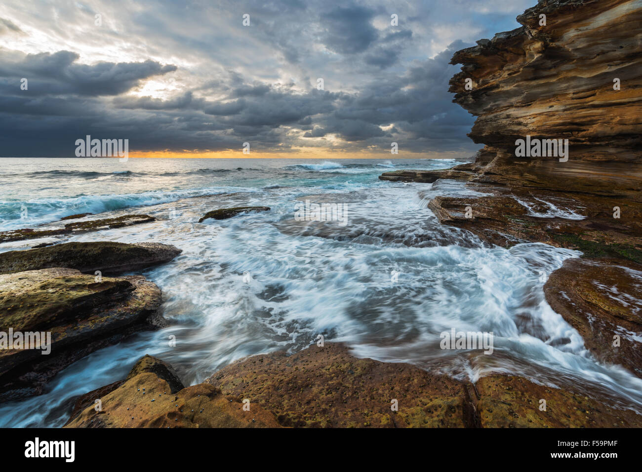 Seascape Sonnenaufgang mit Unruhen Meer und düstere Himmel und Klippen Stockfoto