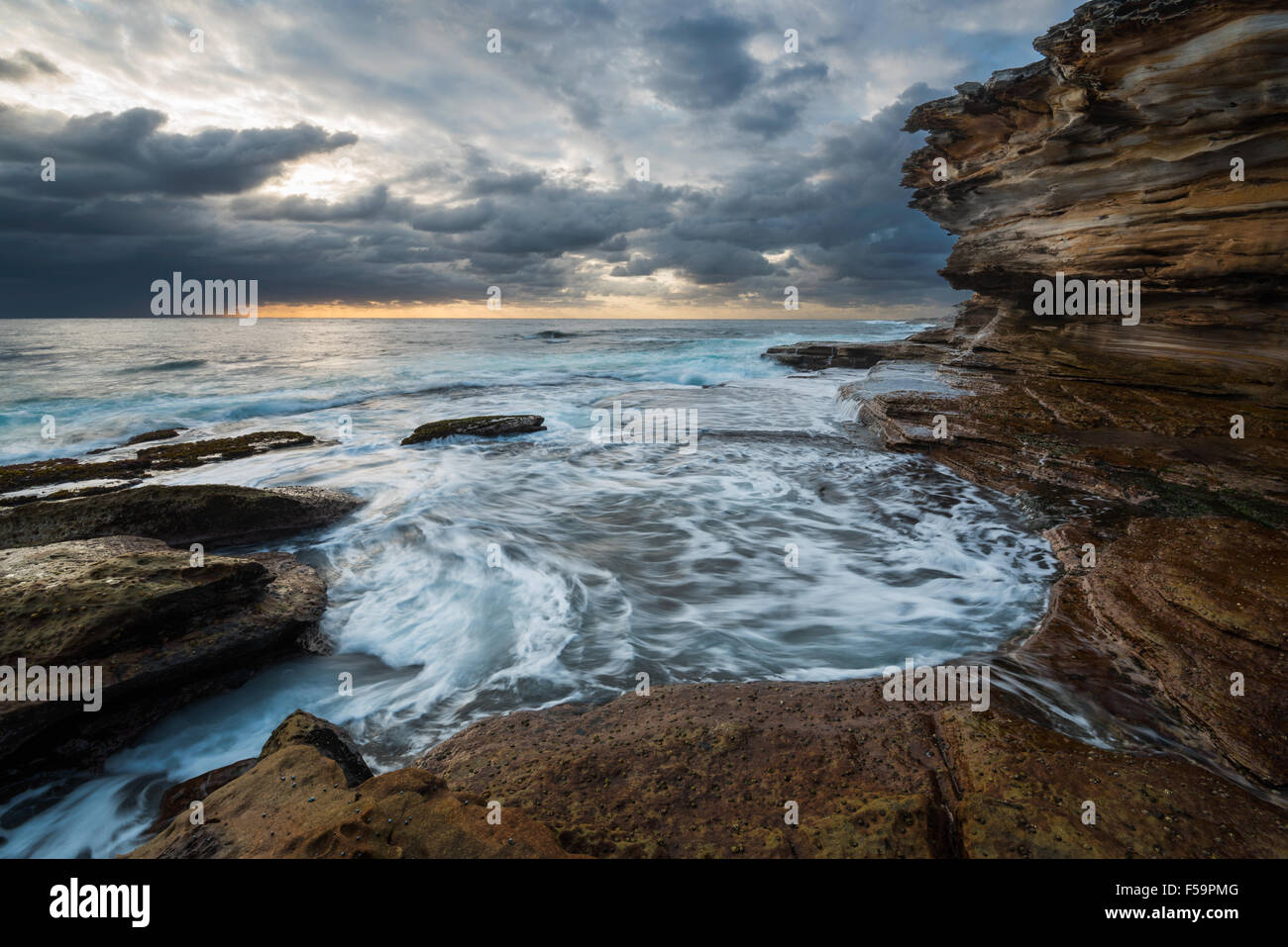 Seascape Sonnenaufgang mit Unruhen Meer und düstere Himmel und Klippen Stockfoto