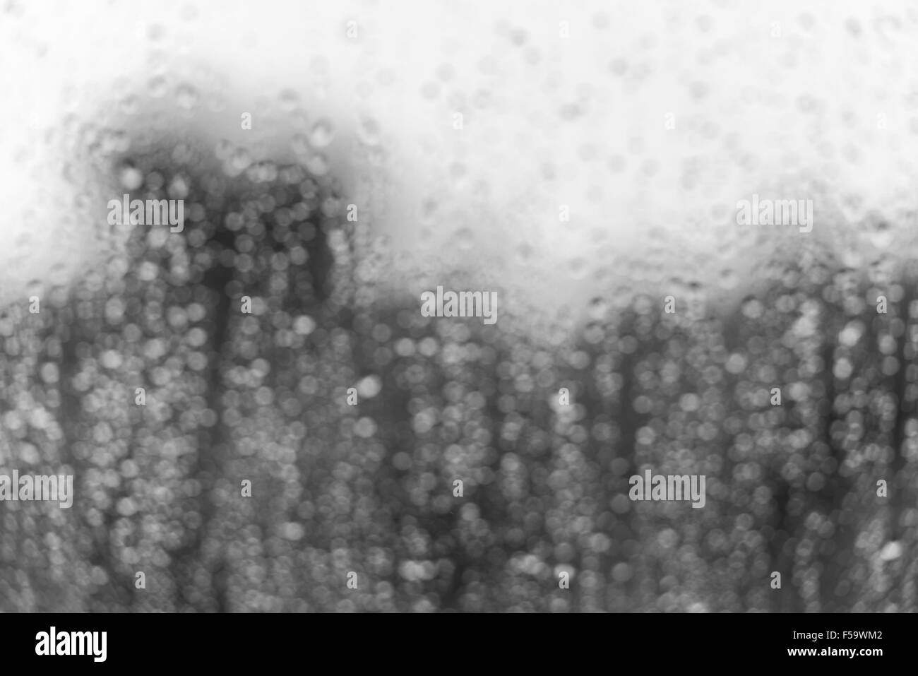 Regen Wassertropfen auf einer Glasfläche Fenster. Defokussierten bw blur Bild mit bokeh Stockfoto