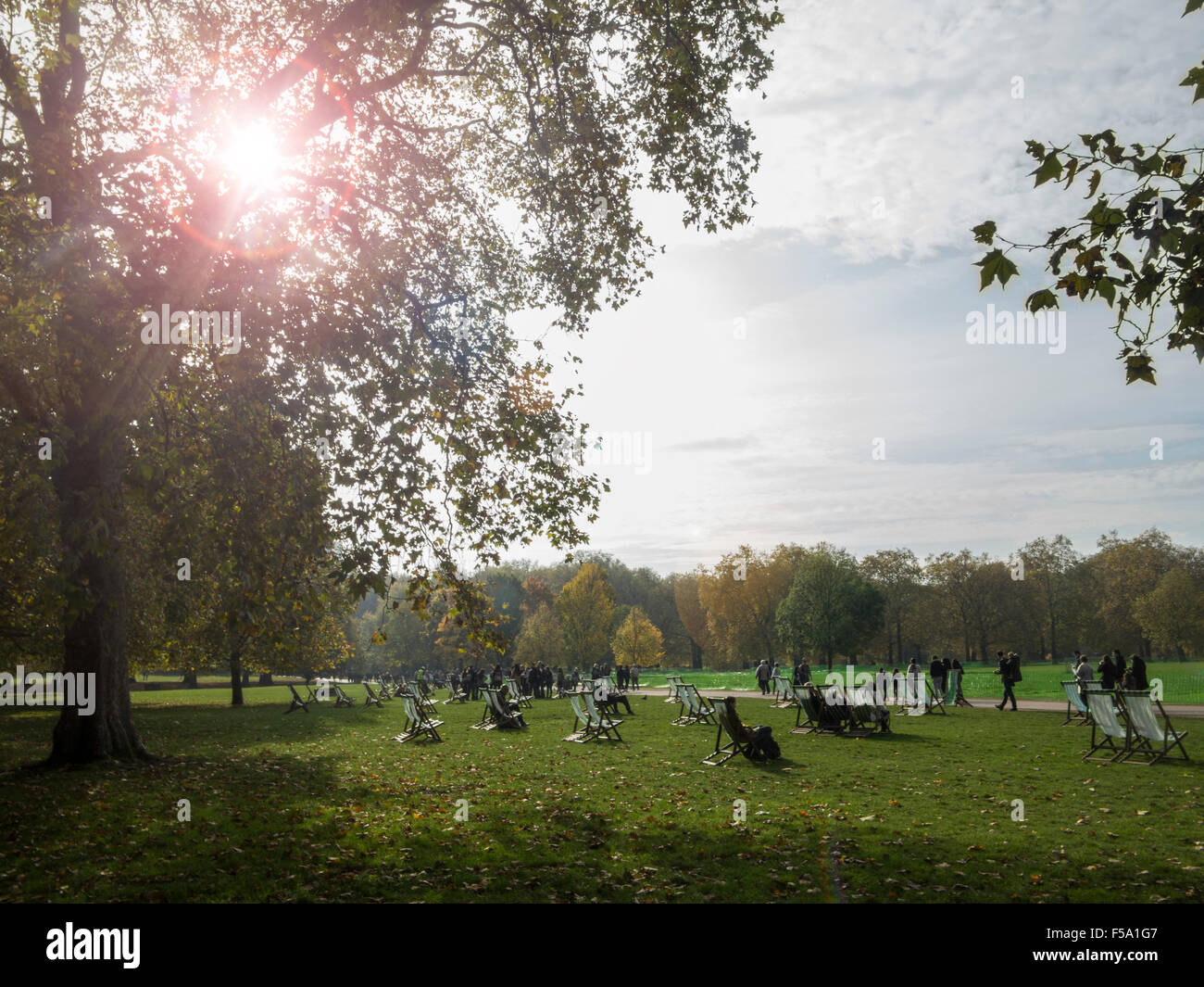 Die Öffentlichkeit genießen Sie ungewöhnlich warme Wetter im November mit den Liegestühlen im St James Park Stockfoto
