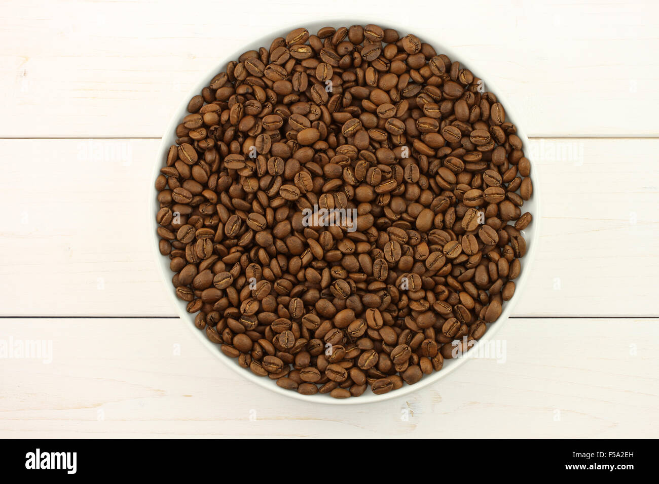 Geröstete Kaffeebohnen in großen weißen Teller auf weißem Holz Hintergrund Stockfoto