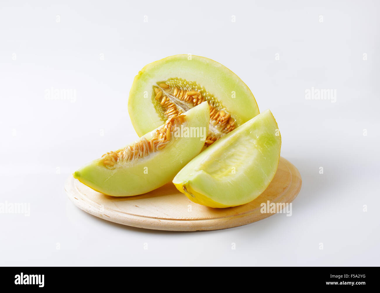 Melone gelb, die Hälfte und Scheiben auf Schneidebrett Stockfoto