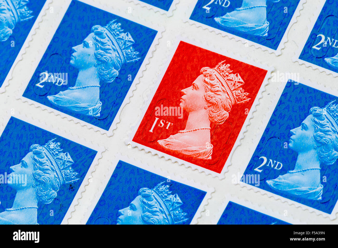 Eine erste 1. Klasse Royal Mail Stempel unter zweiter 2. Klasse Briefmarken Stockfoto
