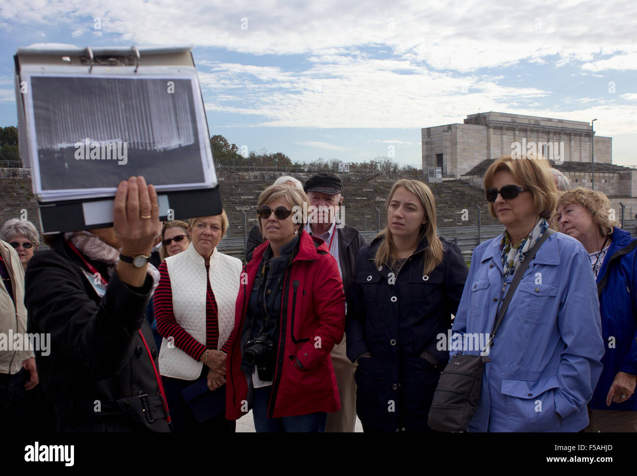 Leitfaden zeigt Touristen wie Zeppelinfeld während einer Kundgebung der NS-Propaganda in den 1930er Jahren mit Stadion & Podium im Hintergrund sah. Stockfoto