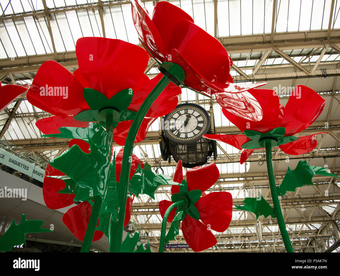 Menschen, die wirbelnden vorbei an einem riesigen Mohn Installation auf das Zusammentreffen der Waterloo Station im Rahmen des London Poppy Day Stockfoto