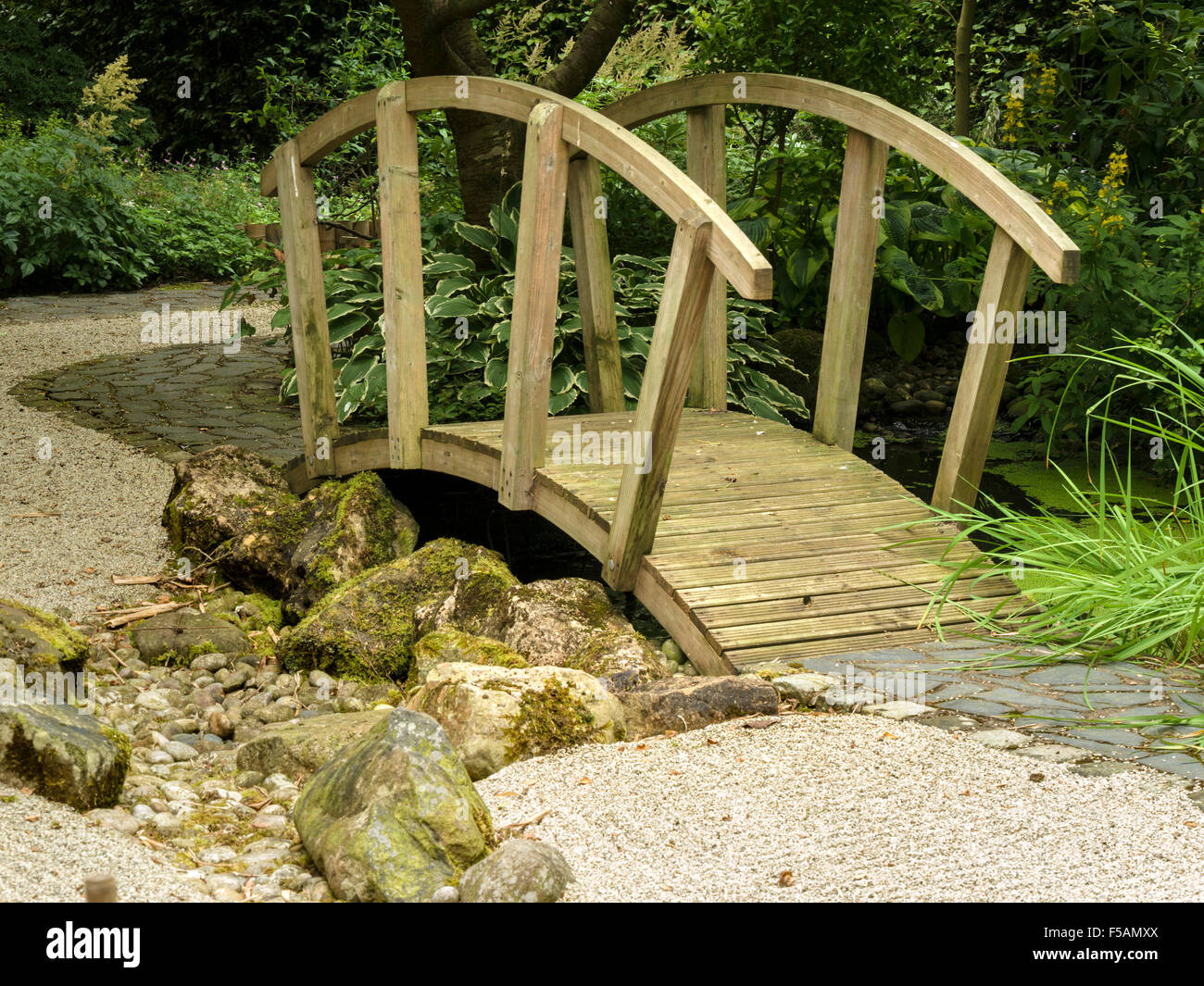 Japanische Zen Stil Garten geharkt Kies und reich verzierte hölzerne Brücke, Barnsdale Gärten, Rutland, England, UK. Stockfoto