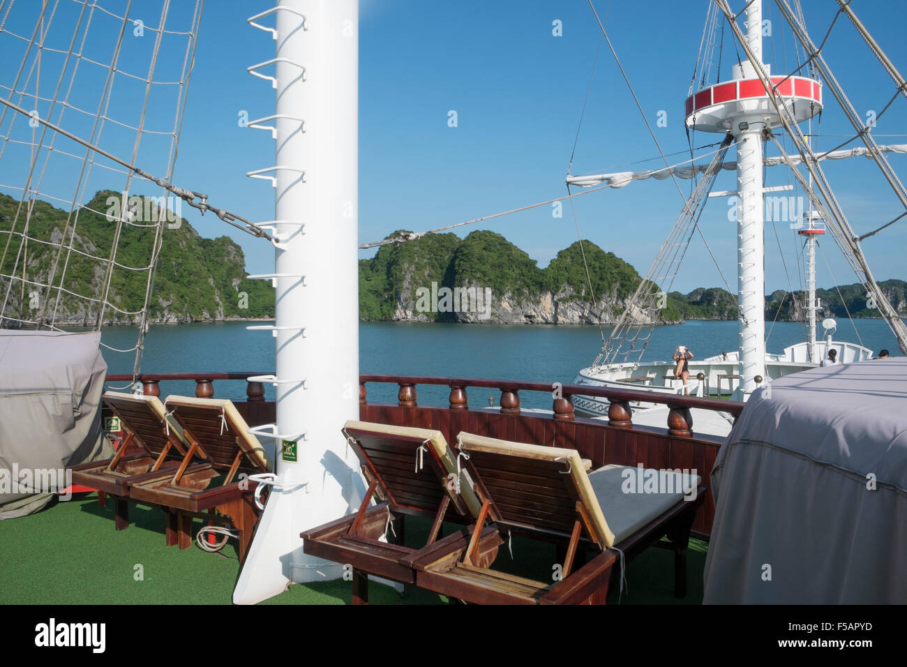 Ha Long Bay Vietnam, Asien, Deck eines luxuriösen Dragon Legend Kreuzfahrtschiffes, das Ha Long Bay mit Liegestühlen und Inseln in der Bucht besichtigt Stockfoto