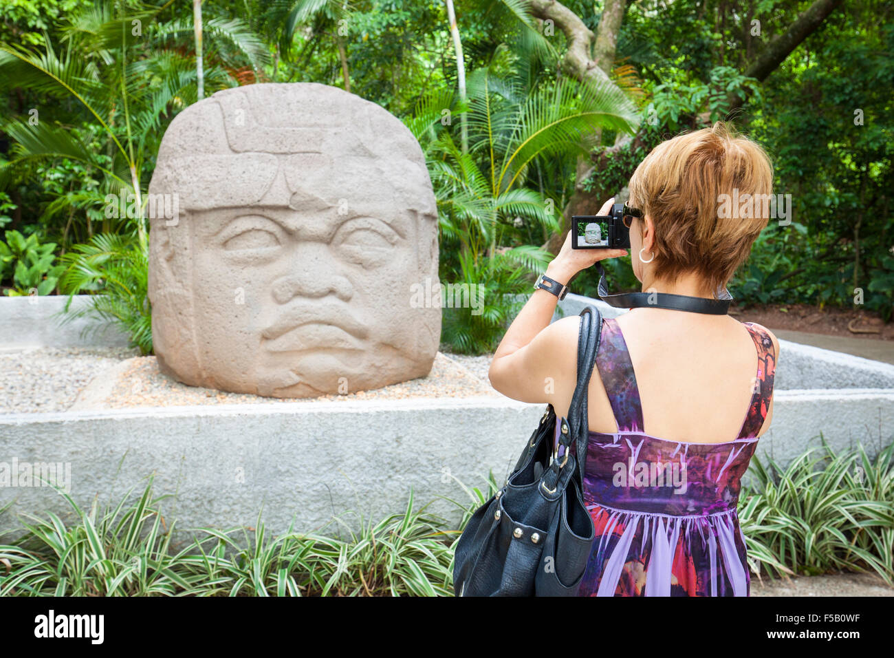 Weibliche Touristen fotografiert die Olmeken Steinbildhauen kolossale Kopf in La Venta Park, Villahermosa, Tabasco, Mexiko. Stockfoto