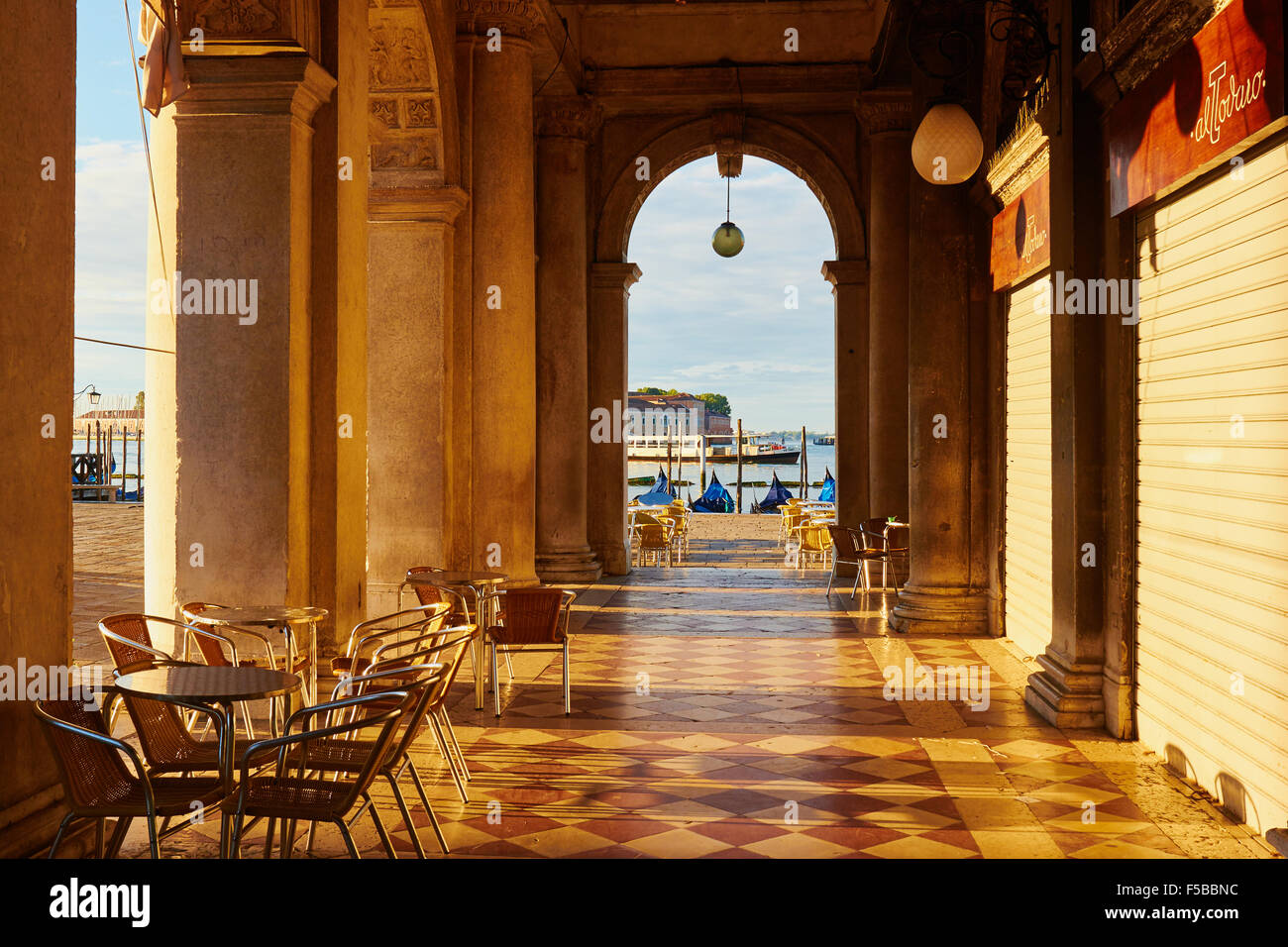 Am frühen Morgensonnenlicht auf einen Colonadded Durchgang in Richtung des venezianischen Lagune Piazzetta San Marco Venice Italiens Stockfoto