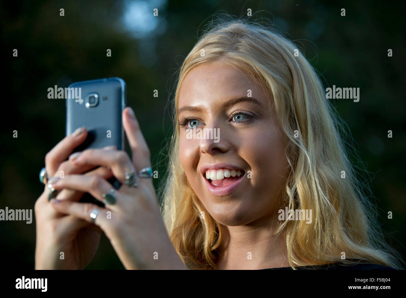 Junge blonde Frau mit Handy im Dunkeln Stockfoto