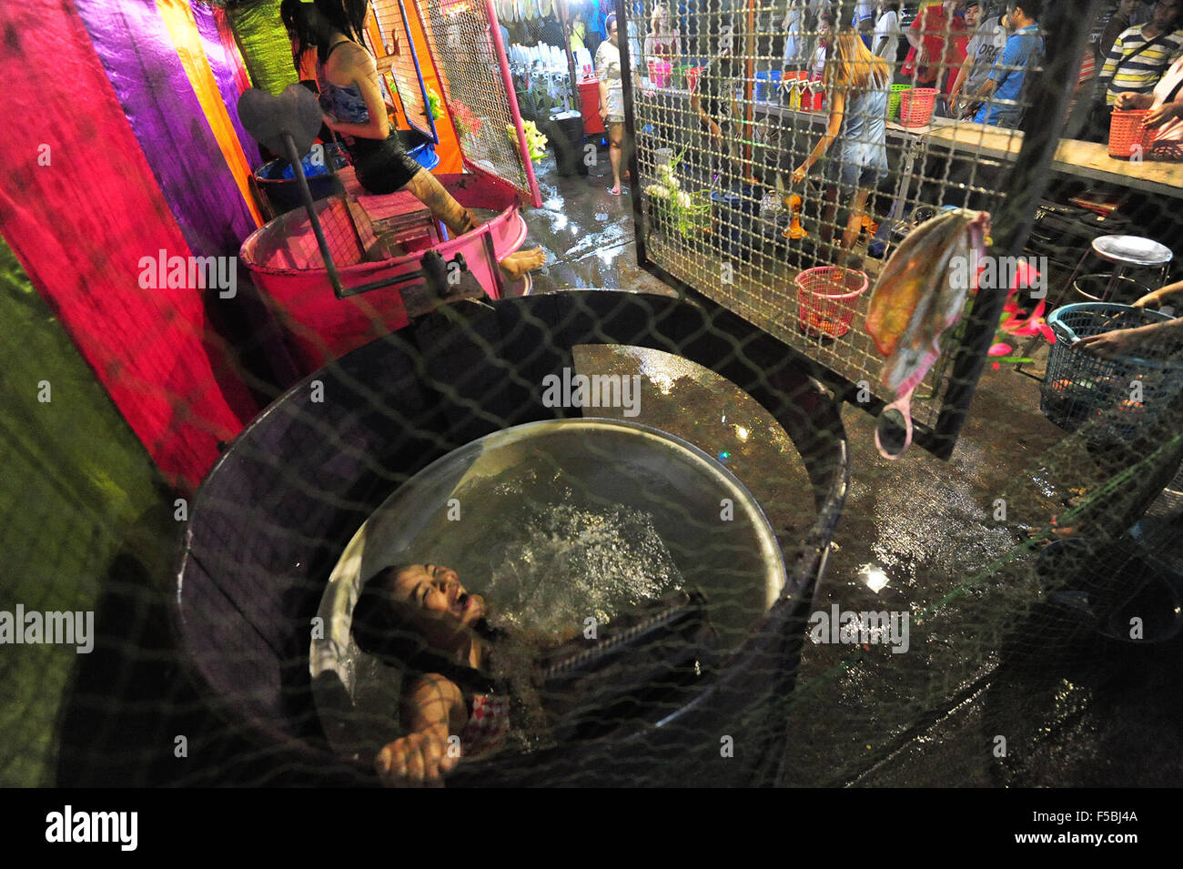 Bangkok, Thailand. 1. November 2015. Ein Dunk Tank Mädchen fällt ins Wasser in Bangkok, Thailand, 1. November 2015. Ein Dunk Tank besteht aus einem Tank Wasser, über die ein Freiwilliger auf einem einstürzenden Sitz sitzt. Wenn ein Ball ein Ziel trifft, der Sitz bricht zusammen und "dunks" die Person ins Wasser. © Rachen Sageamsak/Xinhua/Alamy Live-Nachrichten Stockfoto