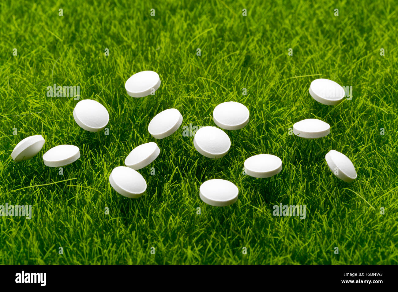 Weiße Antibiotika Pillen, die verstreut auf dem grünen Rasen Stockfoto