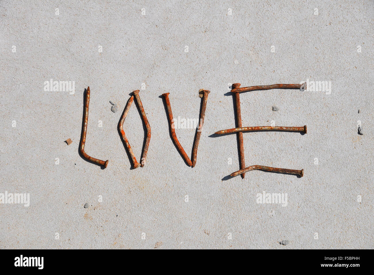 Liebe Wort gebildet von rostigen Nägeln auf grauem Beton Hintergrund Stockfoto
