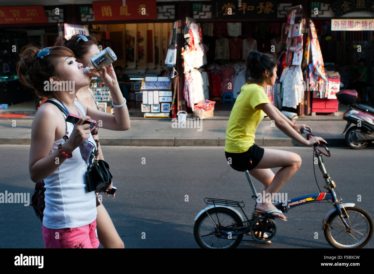Kleine Geschäfte in der Altstadt, Shanghai, China Mädchen und Mädchen mit dem Fahrrad spazieren. Die Altstadt von Shanghai, Shanghai Lă Stockfoto