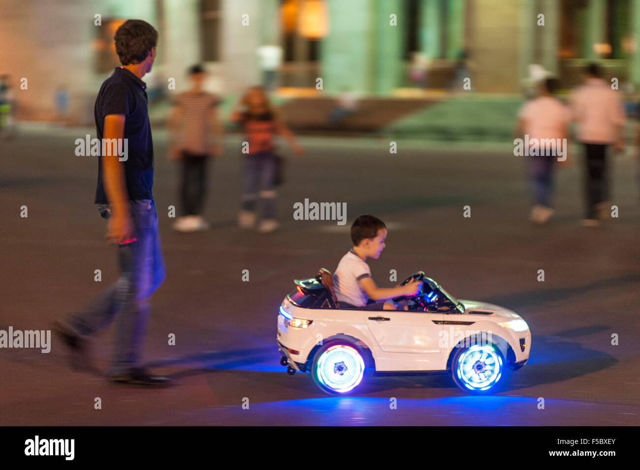 Kind spielt in einem Spielzeugauto außerhalb der Oper in der armenischen Hauptstadt Eriwan. Stockfoto