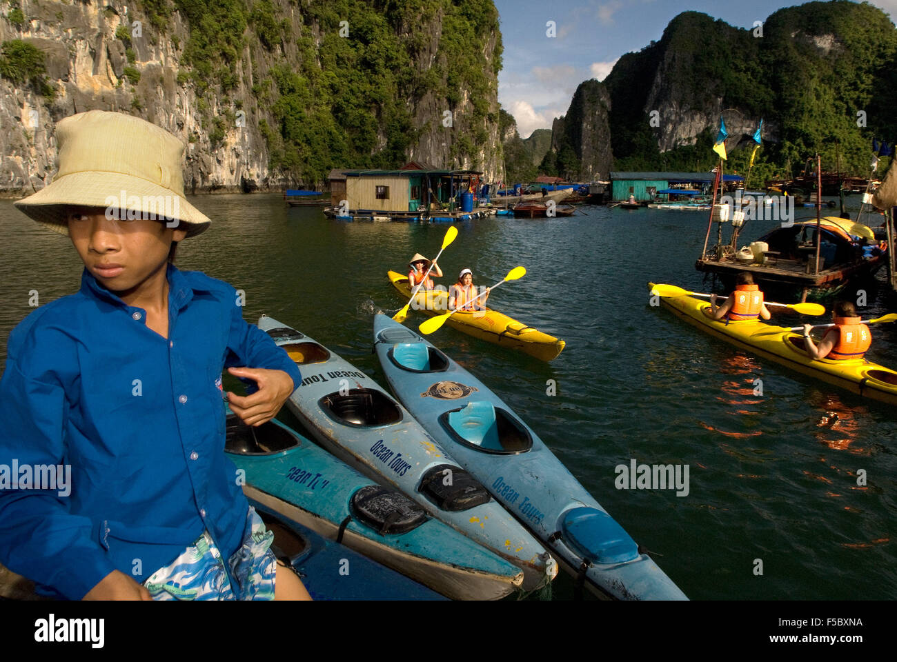 Touristen in mehrere Kajaks aus einem Ausflugsboot in Vietnam Halong-Bucht. Rennfahrer paddeln Seekajaks in der Halong Bay während eines Abenteuers Stockfoto