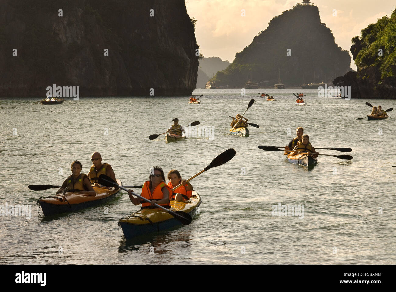 Touristen in mehrere Kajaks aus einem Ausflugsboot in Vietnam Halong-Bucht. Rennfahrer paddeln Seekajaks in der Halong Bay während eines Abenteuers Stockfoto