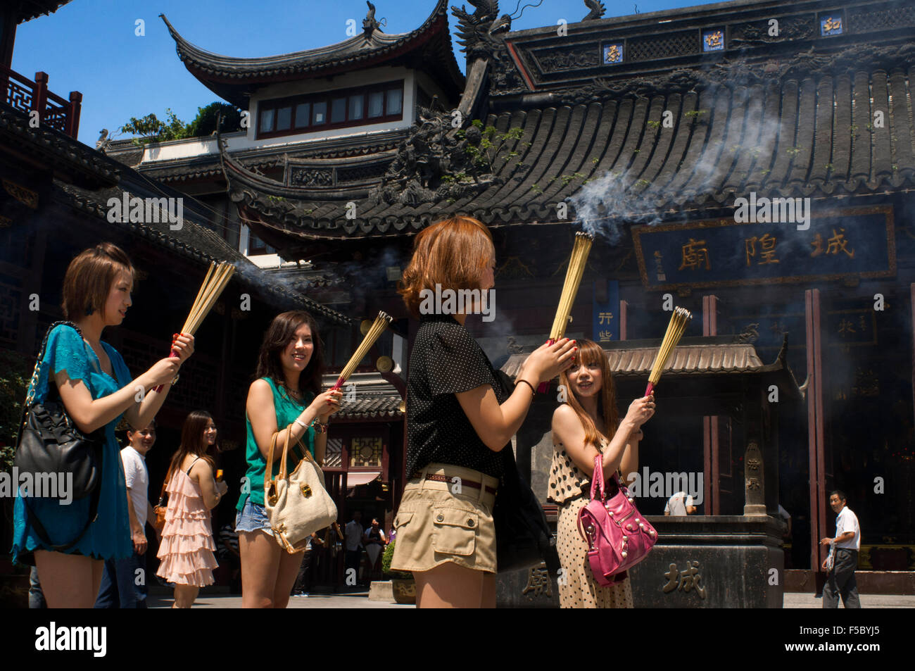Gottes Tempel und Pagoden, buddhistische Tempel in Shanghai, brennende Räucherstäbchen, Weihrauch. Eine Frau betet und lacht über Chenghuang Miao oder Stockfoto