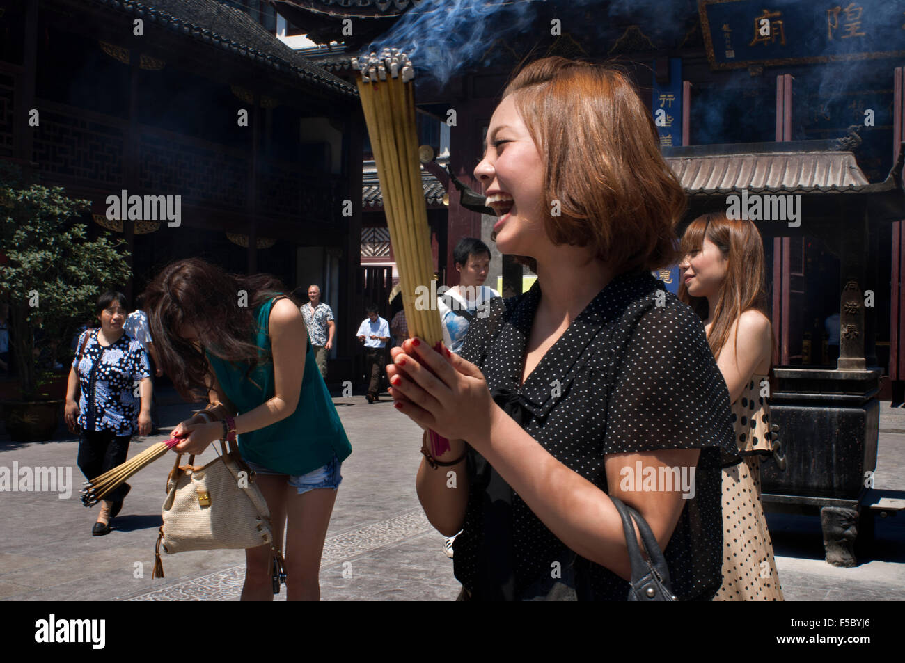 Gottes Tempel und Pagoden, buddhistische Tempel in Shanghai, brennende Räucherstäbchen, Weihrauch. Eine Frau betet und lacht über Chenghuang Miao oder Stockfoto