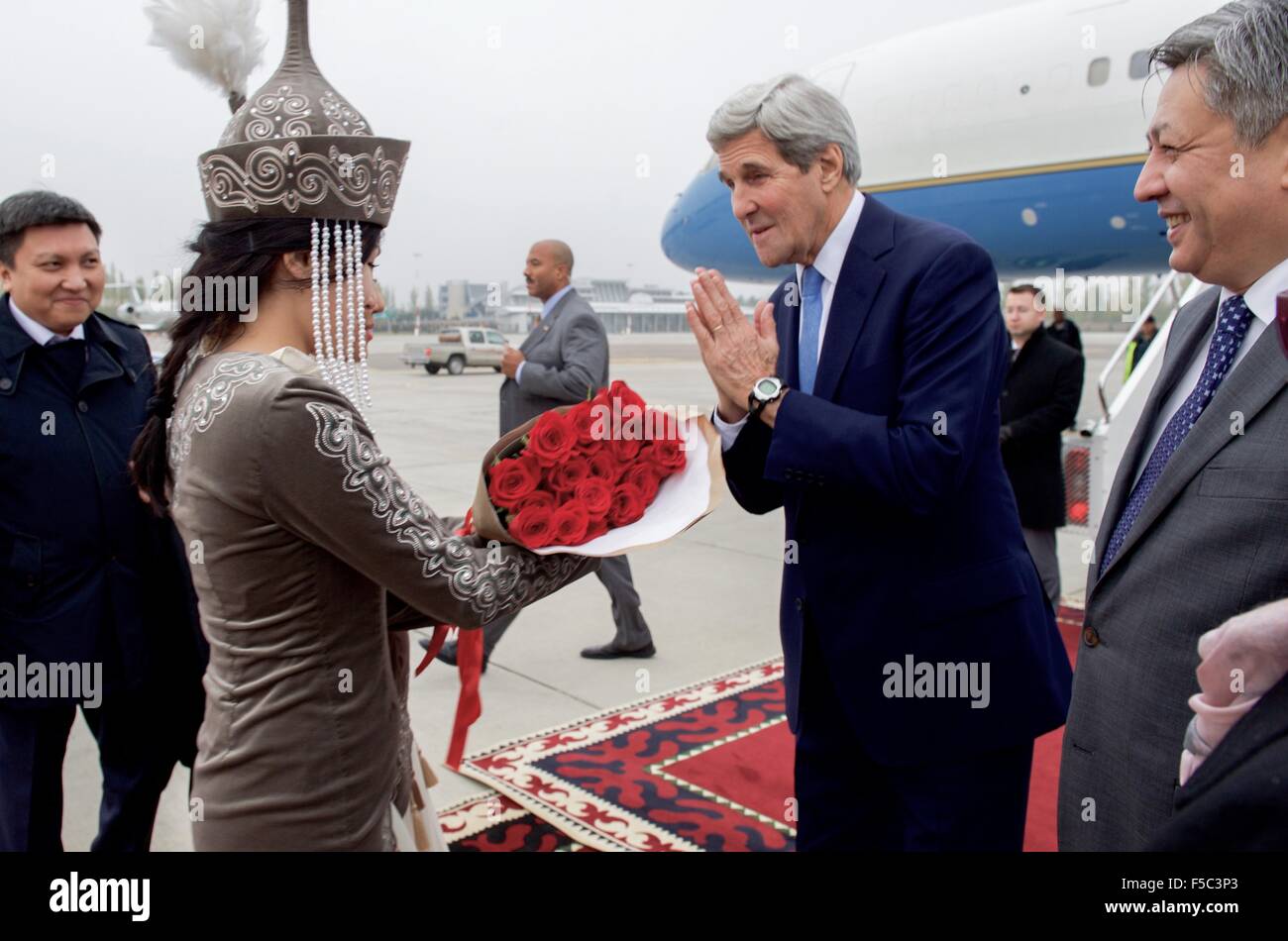 US-Außenminister John Kerry ist eine traditionelle kirgisische einladend aus Frauen in traditioneller Kleidung gegeben, wie Kirgisistan Foreign Minister Erian Abdyldasev am Flughafen Manas 31. Oktober 2015 in Bischkek, Kirgisistan blickt auf. Stockfoto