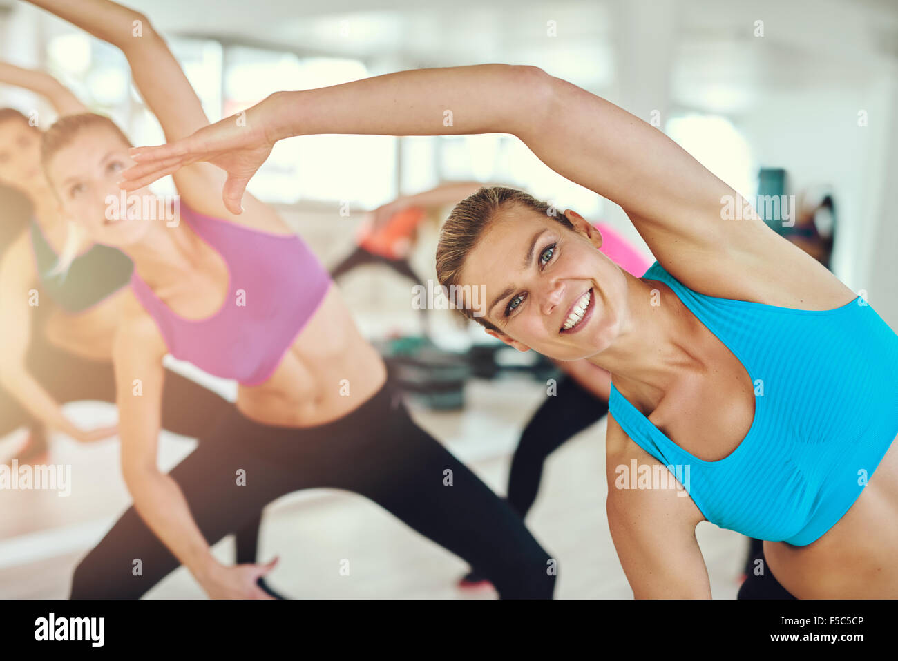 Fitness, Sport, Training und Lifestyle Konzept - Gruppe der lächelnden Frauen Stretching in der Turnhalle Stockfoto