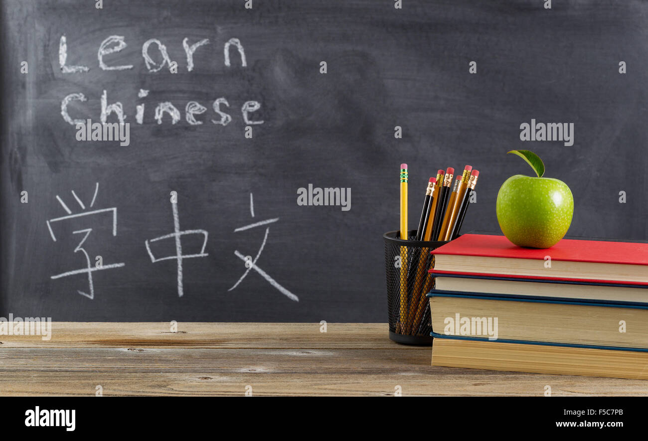 Vorderansicht des rustikalen Schreibtisch für studentisches Lernen Chinesisch mit Bücher, Stifte und ein grüner Apfel Stockfoto