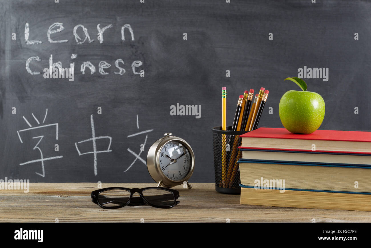 Schüler lernen der chinesischen Sprache mit Bücher, Stifte, Uhr, Lesebrille und einen Apfel vor Tafel mit Mandarin Text. Stockfoto
