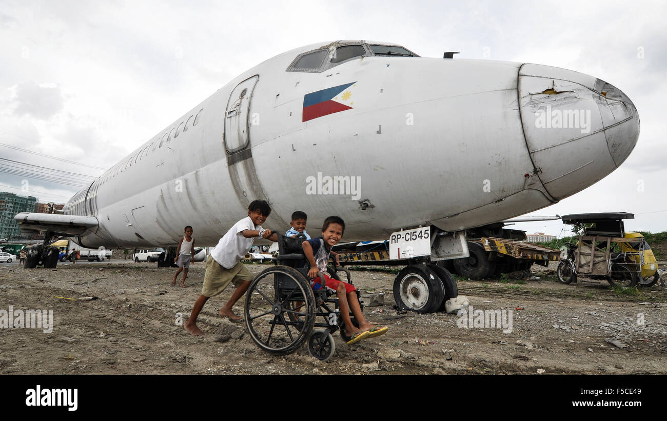 Kinder spielen auf dem Wrack des Flugzeugs auf ein unbebautes Grundstück in Paranaque City, südlich von Manila, Philippinen. Stockfoto